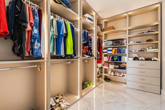 a view of walk in closet with clothes and shoes