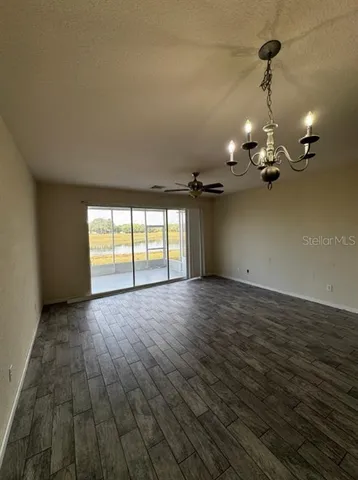 a view of a room with wooden floor ceiling fan and window