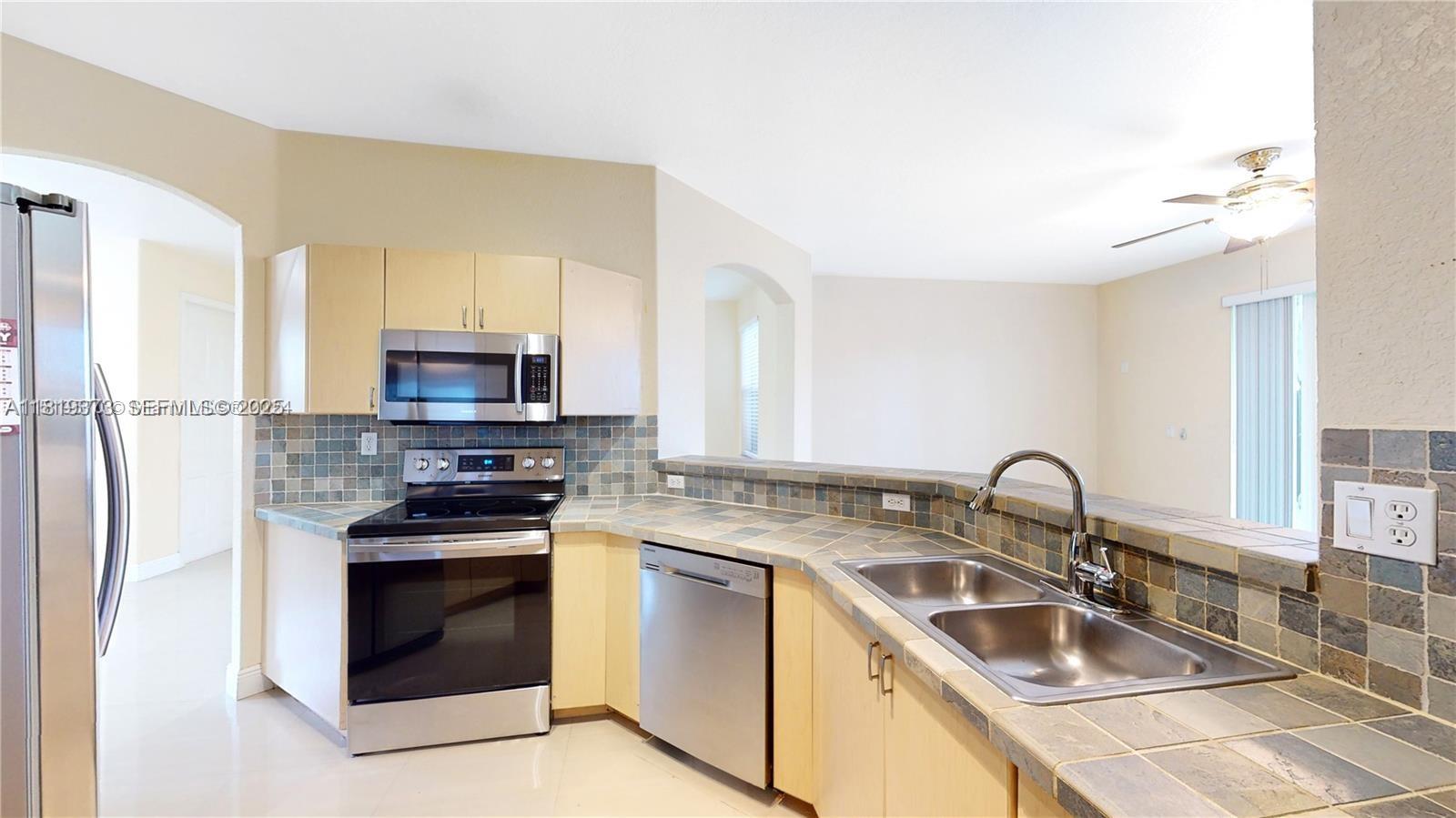 12281 Southwest 121st Terrace Miami, FL 33186 - Photo 11 of 58 a kitchen with stainless steel appliances granite countertop a sink stove oven and refrigerator