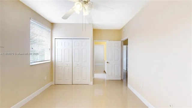 an empty room with windows and fan