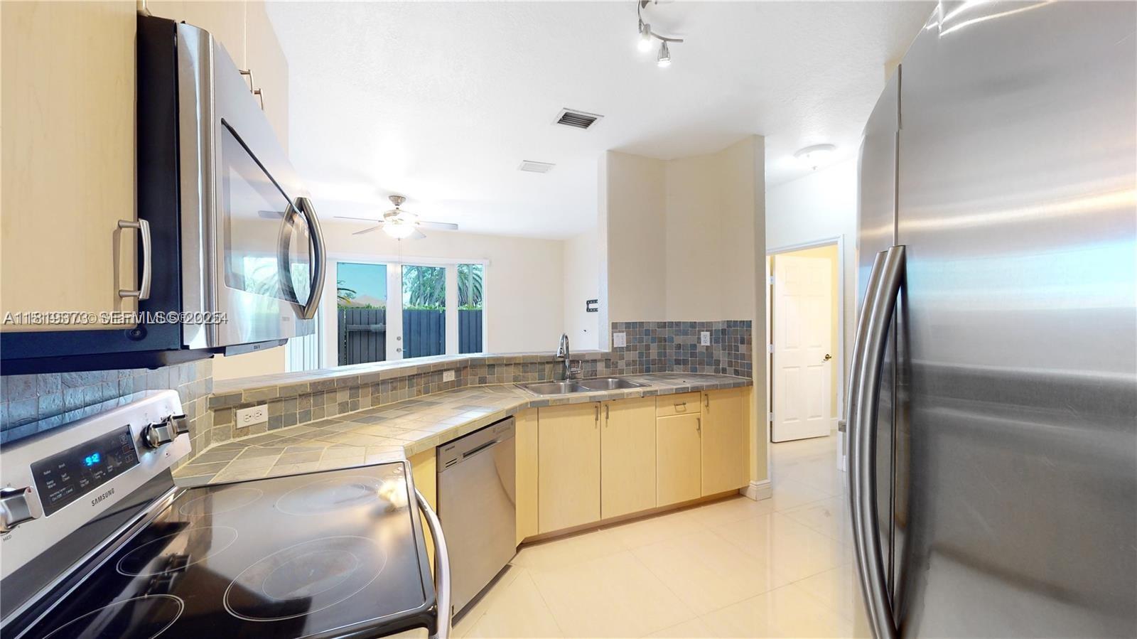 12281 Southwest 121st Terrace Miami, FL 33186 - Photo 10 of 58 a kitchen with stainless steel appliances granite countertop a sink and a refrigerator