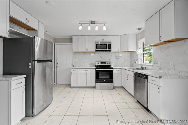 a kitchen with granite countertop stainless steel appliances a sink stove and cabinets