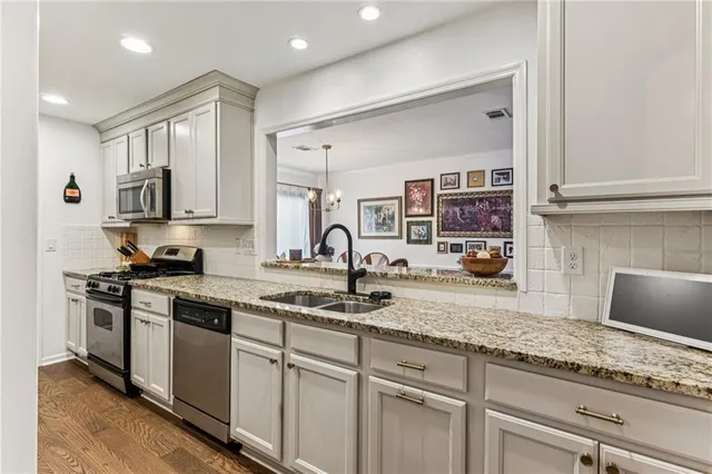 a kitchen with stainless steel appliances granite countertop a stove a sink and white cabinets
