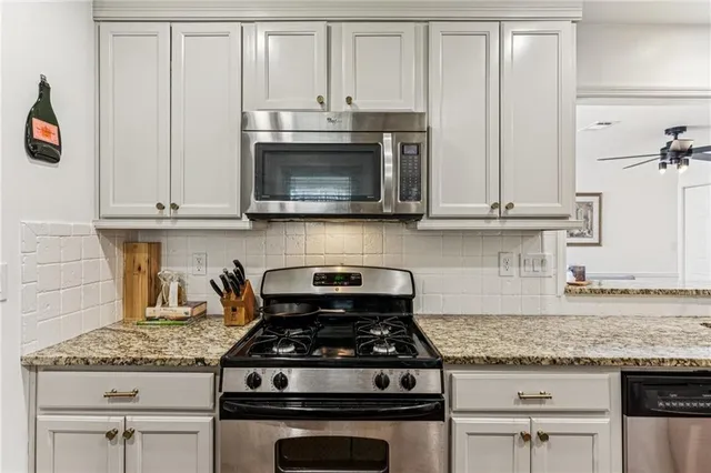 a kitchen with granite countertop a stove and a white cabinets