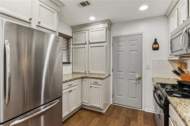 a kitchen with a refrigerator a sink and wooden floor