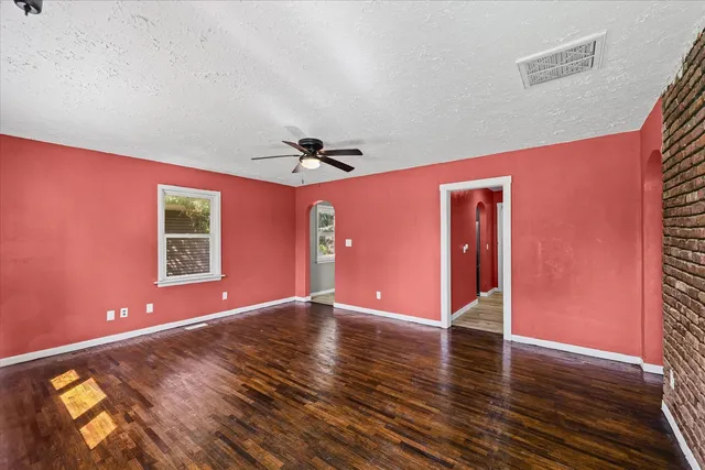 a view of an empty room with window and wooden floor