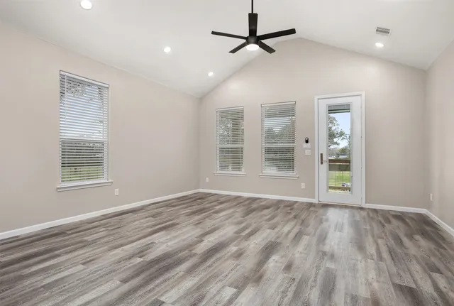 a view of an empty room with wooden floor and a window