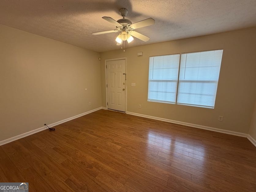 5196 Tew Lane Southwest Covington, GA 30014 - Photo 4 of 41 an empty room with wooden floor chandelier fan and windows