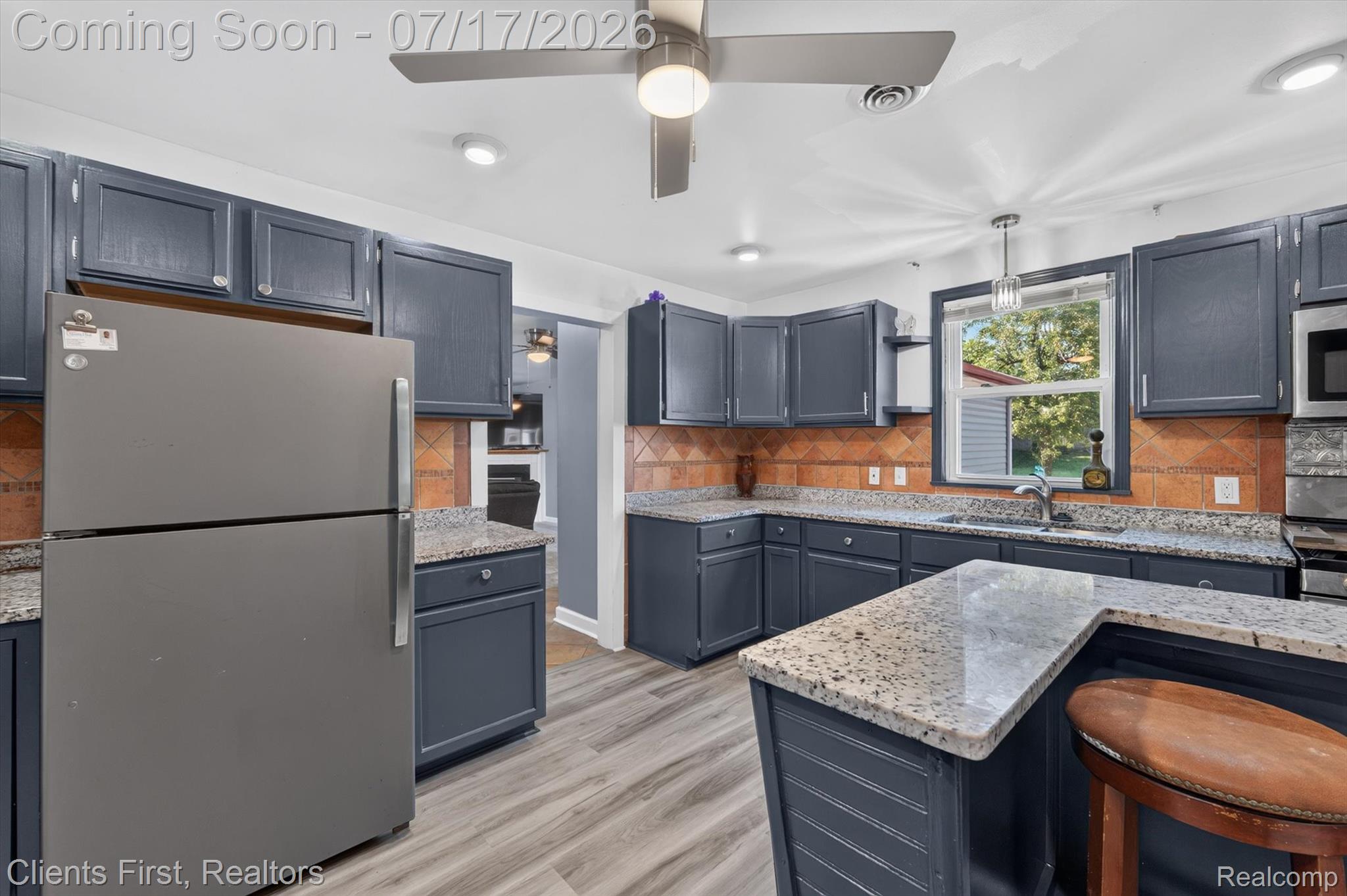 36852 Chase Street Romulus, MI 48174 - Photo 11 of 40 Kitchen featuring dark blue cabinetry, light granite-style countertops, a terracotta-toned tile backsplash, and light wood-finish flooring