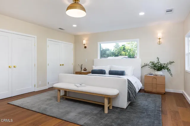 a bed sitting in a spacious bedroom next to a window