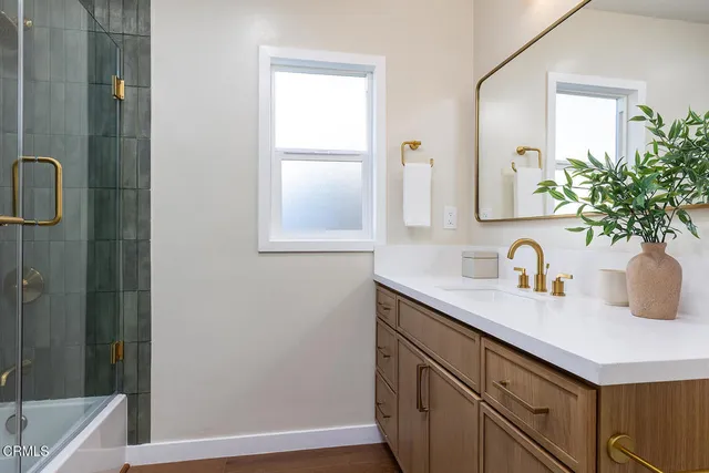a bathroom with a granite countertop sink a mirror and a shower