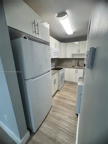 a kitchen with granite countertop a refrigerator a sink and dishwasher