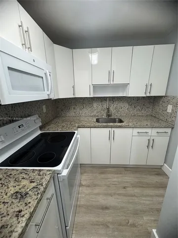 a kitchen with granite countertop white cabinets and white appliances
