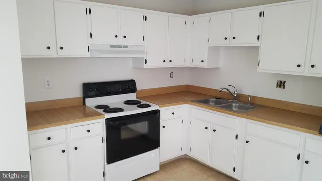 a kitchen with granite countertop white cabinets and white stove