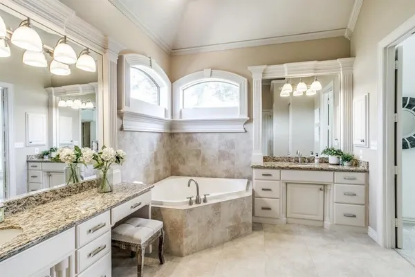 a bathroom with a granite countertop tub a double vanity sink and a large mirror