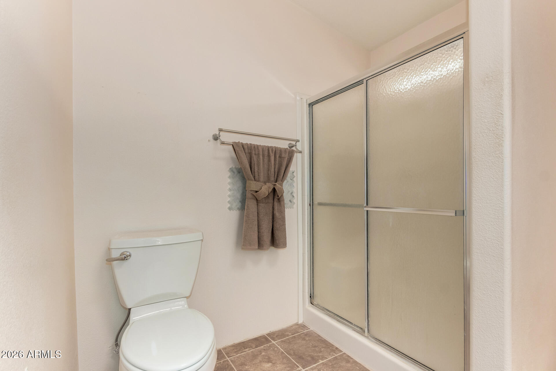23851 West Tether Trail Wittmann, AZ 85361 - Photo 23 of 44 a bathroom with a toilet and a glass shower door