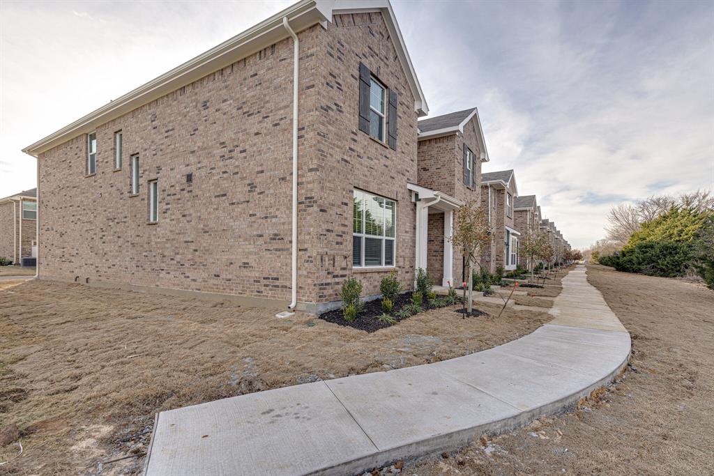 1240 Alamo Drive Lewisville, TX 75077 - Photo 1 of 1 a view of a brick building next to a yard