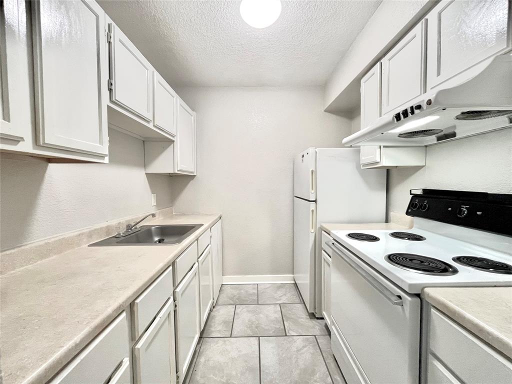 701 West Sycamore Street, Unit 107 Denton, TX 76201 - Photo 4 of 11 a kitchen with a stove and a white cabinets