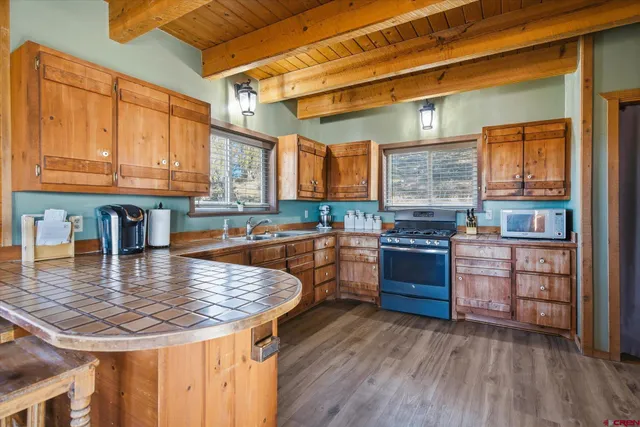 a kitchen with kitchen island granite countertop wooden floors wooden cabinets a counter and a sink