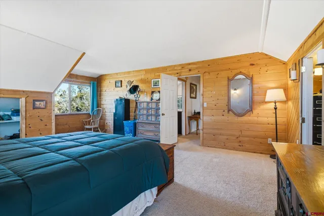 a spacious bedroom with a bed a dresser next to a window