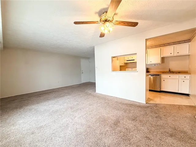 an empty room with chandelier fan and windows