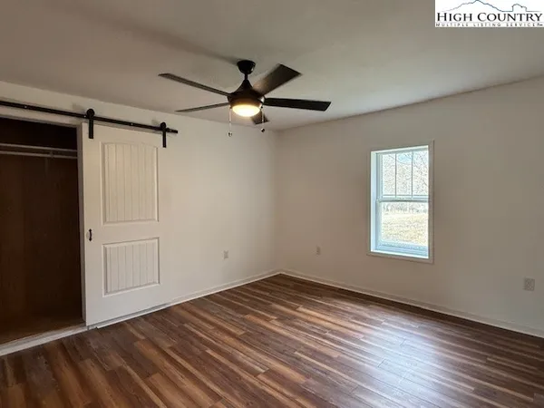 an empty room with wooden floor ceiling fan and windows