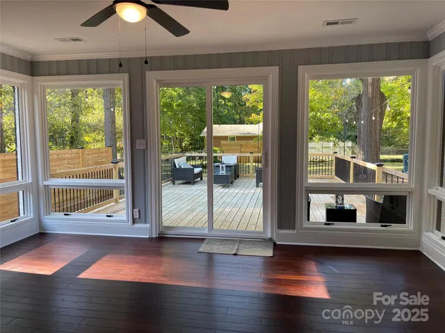 a view of empty room with wooden floor and fan