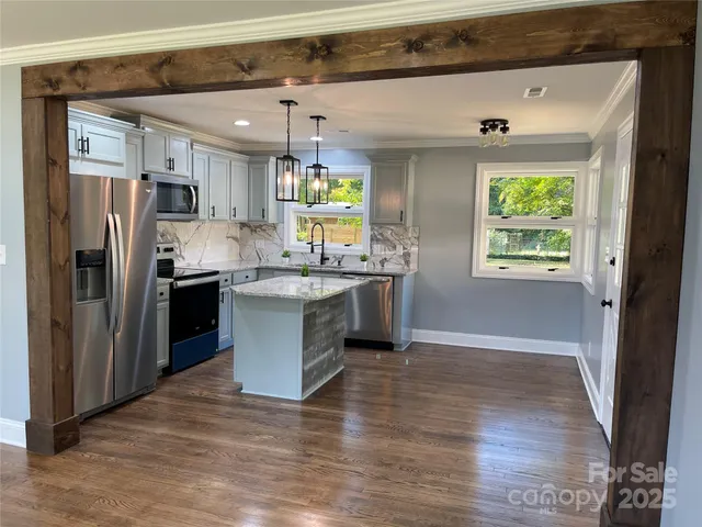 a kitchen with stainless steel appliances granite countertop a refrigerator a sink dishwasher a stove with wooden floor