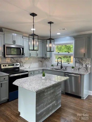 a kitchen with stainless steel appliances granite countertop a sink stove and microwave