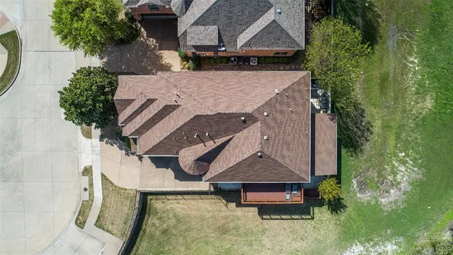an aerial view of a house with swimming pool and large trees