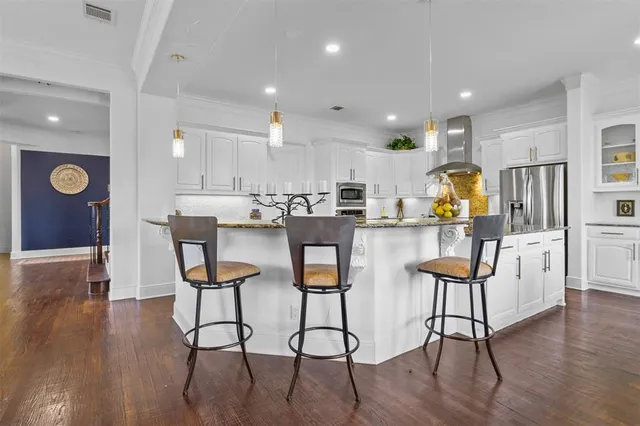 a kitchen with stainless steel appliances kitchen island granite countertop a table chairs refrigerator and microwave