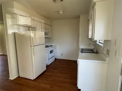 a kitchen with a refrigerator sink stove and wooden floor