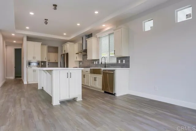 a kitchen with stainless steel appliances granite countertop a white cabinets a sink a stove a refrigerator and a microwave