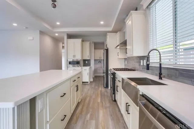 a kitchen with granite countertop a sink a counter space appliances and cabinets
