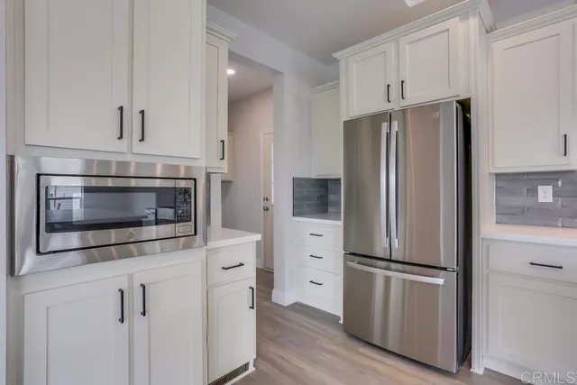 a kitchen with white cabinets and stainless steel appliances