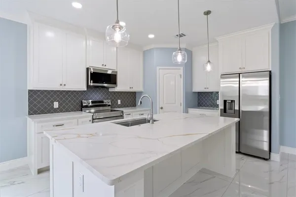 a kitchen with kitchen island granite countertop a sink a center island and stainless steel appliances
