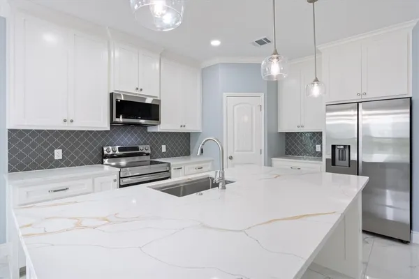 a kitchen with stainless steel appliances a stove a sink a refrigerator a center island and cabinets