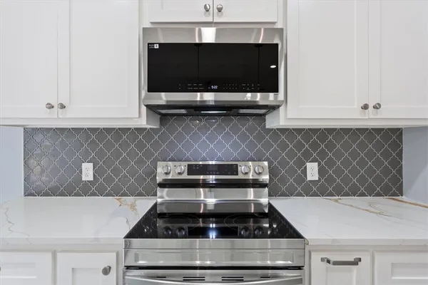 a kitchen with a stove and white cabinets