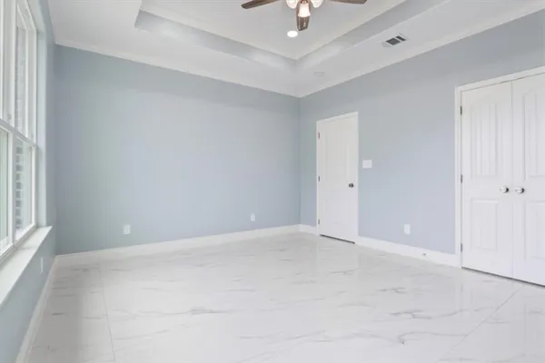 an empty room with a chandelier fan and windows