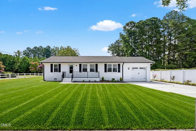 a view of a house with a big yard and a large tree