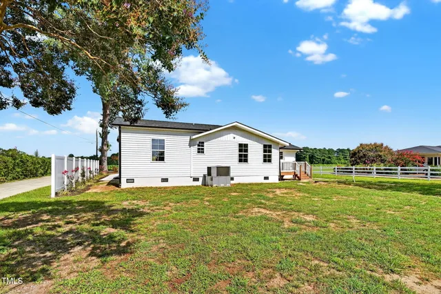 a house that is sitting in the grass with large trees
