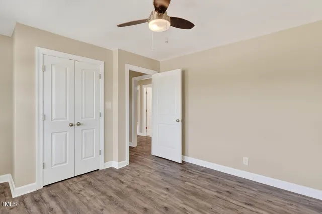 an empty room with wooden floor a ceiling fan and windows