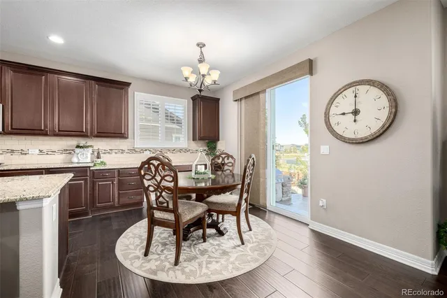 a kitchen with stainless steel appliances granite countertop a refrigerator a stove a sink dishwasher a dining table and chairs with wooden floor