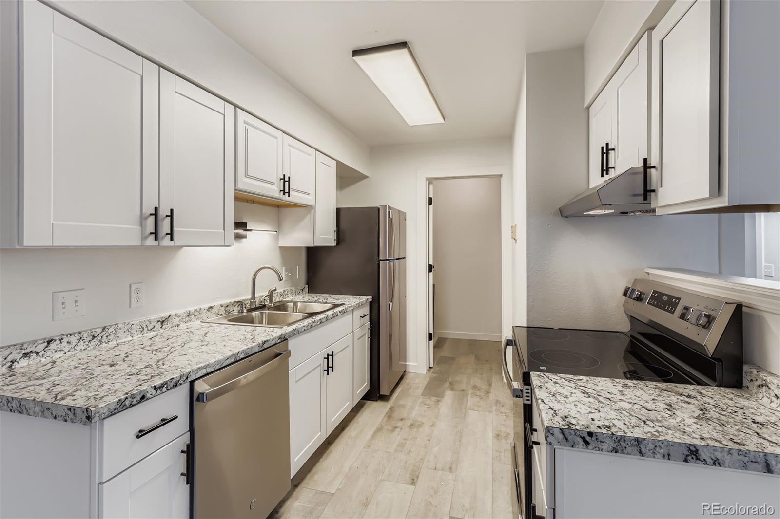 1845 Kendall Street, Unit 103A Denver, CO 80214 - Photo 4 of 11 a kitchen with stainless steel appliances granite countertop a sink stove and refrigerator