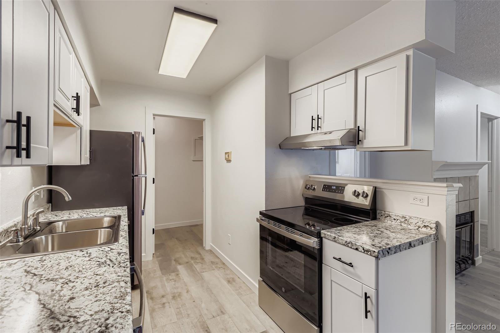 1845 Kendall Street, Unit 103A Denver, CO 80214 - Photo 5 of 11 a kitchen with granite countertop a sink stove and refrigerator