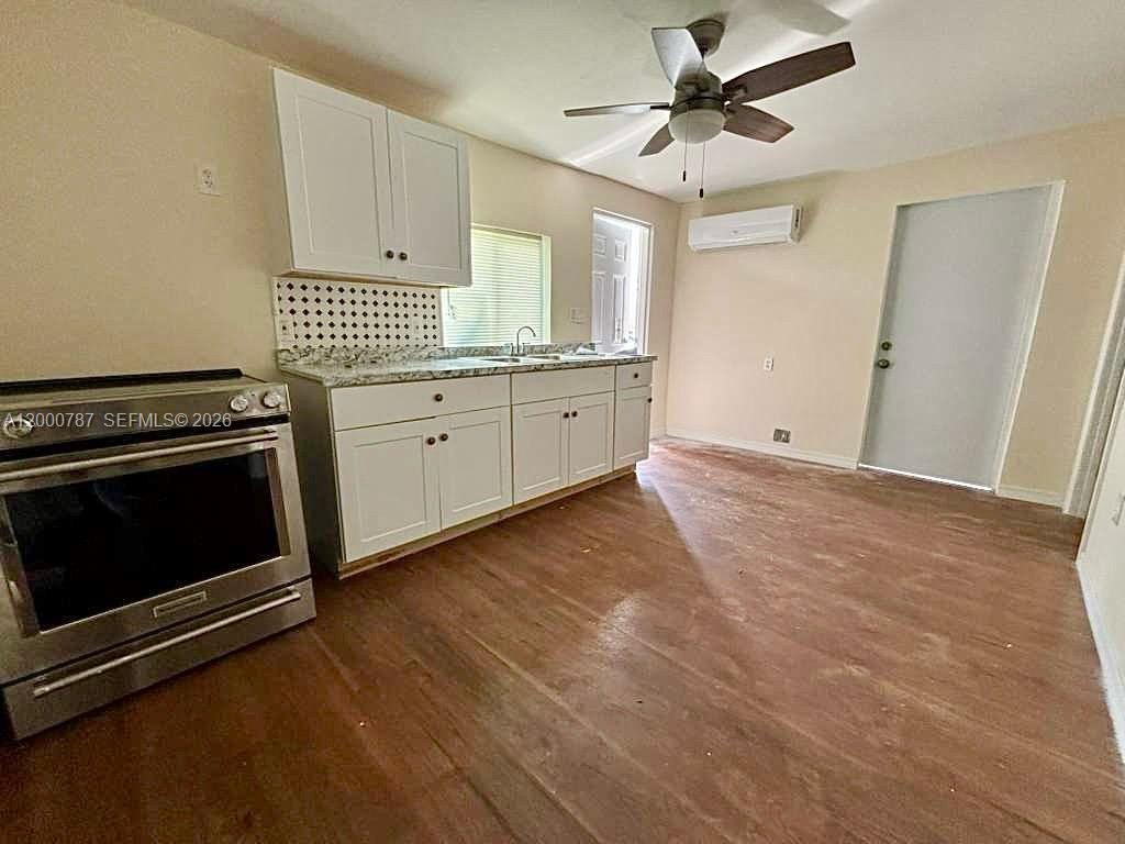 a kitchen with granite countertop a stove a sink and white cabinets