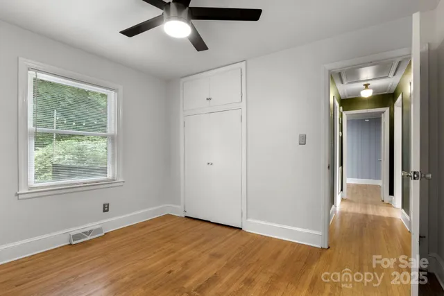 a view of an empty room with wooden floor and a window