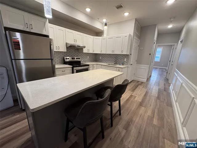 a kitchen with stainless steel appliances a refrigerator a sink a stove a dining table and chairs