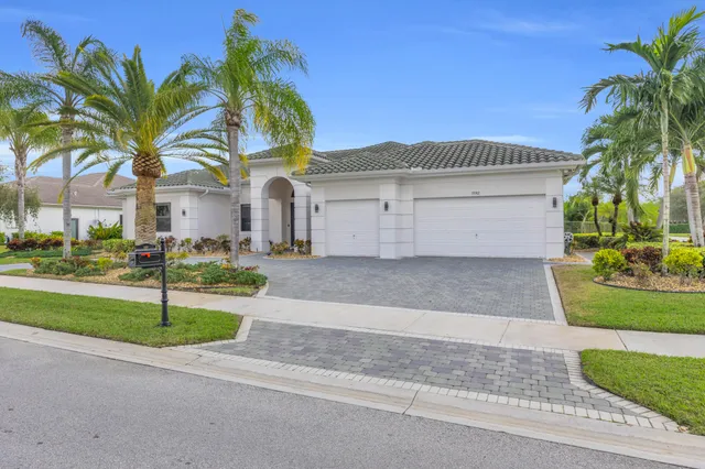 a view of a white house with a small yard and palm trees