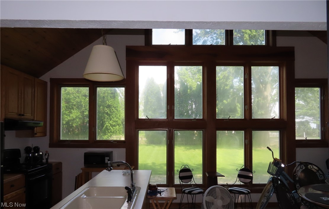 182 Harcourt Road Vermilion, OH 44089 - Photo 4 of 29 Kitchen featuring range, vaulted ceiling, a healthy amount of sunlight, and decorative light fixtures